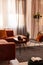 Elegant small wooden coffee table with lowers in front of big velvet corner sofa with pillows