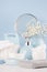 Elegant soft bathroom dressing table with products for body and skin care, white flowers, towels, mirror, ceramic blue vase.