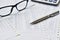 Elegant stainless steel pens on a pile of paper documents with blurred glasses is background.