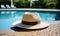 Elegant straw fedora hat resting on a poolside under the tranquil summer sun, symbolizing leisure, vacation, and the serene joy of