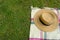 Elegant straw female hat with black ribbon on checkered blanket on grass. top view. summer picnic in the park. Copy space