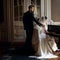 elegant stylish handsome groom hugging gently gorgeous bride while playing the fortepiano. unusual luxury wedding couple in retro