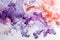Elegant swirls of purple and coral ink diffuse beautifully in water, creating a mesmerizing abstract design.