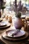 Elegant table with porcelain tableware, crystal glasses, vases and flowers in lavender tones