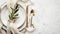 Elegant table setting with white plates, gold cutlery, and olive branch