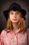 Elegant teen girl wearing black hat on dark background. Youth fashion.