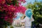 Elegant traveler woman with straw hat smelling beautiful colorful flowers on the islands of Greece during summer time. Romantic