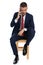 Elegant unshaved businessman with elbow on knee talking on the phone