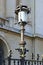 Elegant vintage lantern is lit by the bright sun. Ancient building in the background. Lamp post on a street in the Old Centre