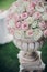 Elegant wedding bouquet on column, stylish decor of wedding aisle outdoors. Pink and white roses arrangement at wedding reception