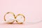 Elegant Wedding or Engagement background - pair of golden wedding rings on light pink background
