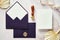 Elegant wedding stationery top view. Flat lay purple envelopes, paper card, dried flowers, wax seal stamp on marble desk