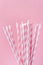 Elegant White Paper Drinking Straws with Pink Stripes Pattern Ornament on Fuchsia Background. Birthday Party Fun Kids Holiday