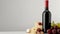 Elegant wine setup with a red wine bottle, assorted cheeses, and grapes on a wooden board against a gray background