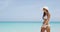 Elegant woman on beach enjoying summer travel in bikini wearing sunglasses