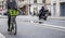 Elegant woman cyclist rides rented bike with basket along the modern street of Paris