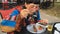 Elegant woman in fashionable clothes and red glasses eats meat at an outdoor cafe.