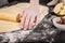 Elegant woman hand holding a rolling pin and prepares the dough for buns. Close-up. Step by step recipe