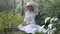 Elegant woman in hat seating with summer flowers outdoors