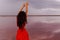 Elegant Woman In Red Silky Dress Walking By A Salt fantastic Lake At Sunset.