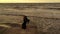 Elegant woman with scarf dancing on pier. Drone view. Sea with waves. Glamorous lady in black long dress