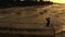 Elegant woman with scarf dancing on pier. Drone view. Sea with waves. Glamorous lady in black long dress