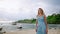 Elegant woman strolls on tropical beach in blue dress, sun-kissed skin gleaming. Luxurious vacation, resort wear