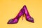 Elegant women`s shoes with high heel and glamor decorations on a yellow background