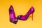 Elegant women`s shoes with high heel and glamor decorations on a yellow background