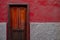 Elegant wooden dark varnished wood door. House with burgundy red wall. Architecture detail.