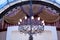 Elegant wrought iron chandelier on the ceiling against the backdrop of curtains