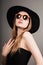 Elegant young blond lady in sun glasses and black hat looking confidant. Closeup