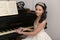 Elegant young brunette with oriental appearance in a white dress at the piano