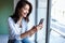 Elegant young business woman smiling and taking a photograph through the window in the office