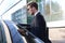 Elegant young businessman entering his car while standing outdoors