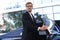 Elegant young businessman entering his car while standing outdoors