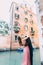 Elegant young couple kissing and hugging on the background of ancient orange building and canal in Venice, Italy