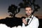 Elegant young fashion man in tuxedo shot at sunset in Joshua Tree National Park, California, USA