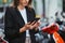 An elegant young girl in a business suit uses mobile app in her smartphone to remotely activate and pre pay for a street scooter