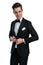 Elegant young groom in tuxedo looking to side and arranging coat