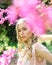 Elegant young lady enjoying walk in blooming garden, spring time concept. Portrait of beautiful girl with long, blond