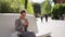 elegant young mixed race woman sitting on stone bench in city square, waiting for someone and using her phone. girl