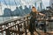 Elegant young woman dressed in fashionable jumpsuit standing on the Brooklyn Bridge.