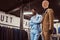 Elegantly dressed African-American man posing with crossed arms near mannequin in a classic menswear store.