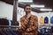 Elegantly dressed African man posing with hand on chin while standing in a classic menswear store.