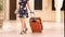 Elegantly dressed young woman carrying luggage hotel, summer vacation, tourism