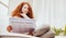 Elegantly seated, redhead studies business in sunlight