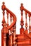 Element of a wooden staircase with carved curved balusters and mahogany railings, isolated on a white background
