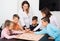 Elementary age joyous children at table with board game and dice