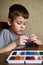 Elementary school age Caucasian child boy plays with plasticine on table, modeling clay, molds, sculpture